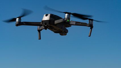 A flying mini drone recording video and photos in the sky over construction