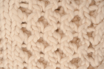 A fragment of beige knitted fabric, knitted from white sheep wool.
