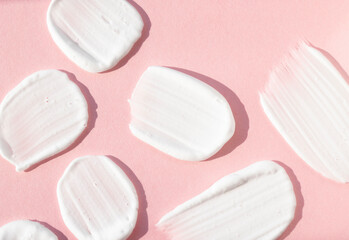 Smears of white cosmetic cream on a pink background, top view. Cosmetic foam, soaps, product for hygiene and care.