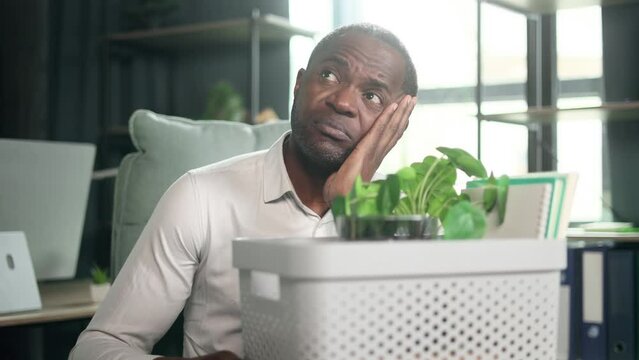 Portrait of fired sad african american businessman carries his box with personal belongings need to leave the office Pensive mature man thinking about future after unemployed looking around indoors