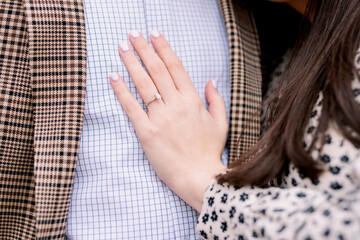 Woman has her hands on her fiance's chest, she is showing off her engagement ring