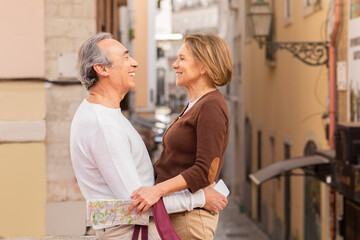 Senior Spouses Hugging Standing On Street In European City Outside