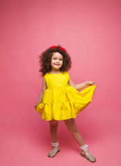 portrait of a girl in a yellow dress cute attractive cute cheerful cheerful little girl .isolated pink background.