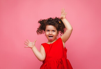 emotional portrait of a little girl in a red dress on a pink background.