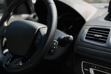 Fototapeta na wymiar Perforated leather steering wheel in the interior of a luxury modern car.