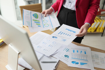 Woman sorts document papers with statistics and diagrams