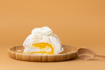 Cut of homemade meringue roll filled with mango puree and decorated with almond flakes, on the...