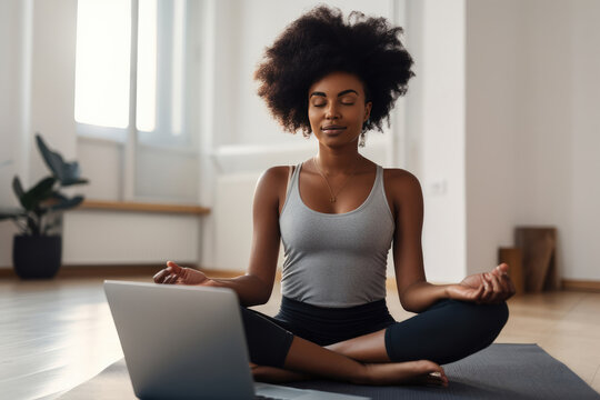 Young black woman sitting on the floor at home doing yoga breathing exercise, in a virtual class on her laptop. Generative AI