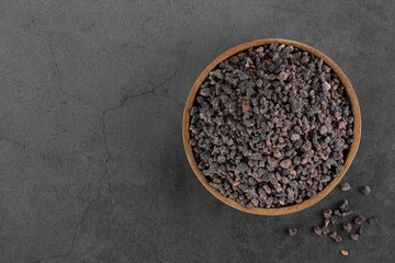 Himalayan crystal black salt in a wooden bowl on a gray background. Spices background. Flatley. Copy space.