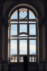 Cloudy sky seen through a tall, ornate window
