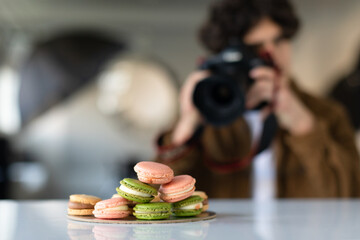 Young man with professional camera taking food photo, working in photostudio, selective focus