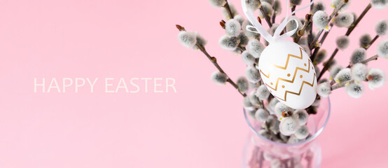 Easter holiday composition. Pussy willow branches decorated easter eggs on pink table background....