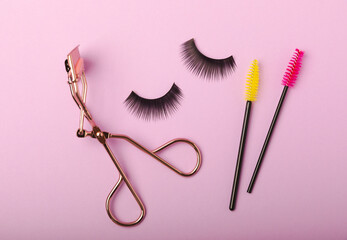Composition with false eyelashes, mascara and eyelash brushes, eyelash curlers on a lilac...