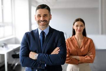 Portrait of two business leaders partners posing with folded arms and smiling at camera, working...