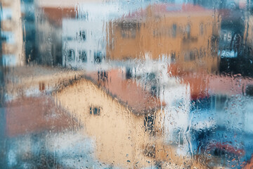 View of city through the window in raindrops during downpour