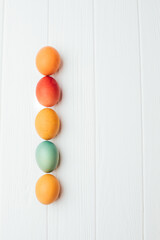 Colored eggs of different sizes on a white wooden background. Symbol of the Easter holiday. Easter background, top view