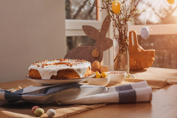 Round Easter cupcake decorated with white protein cream and colorful sprinkles on a wooden table in the kitchen. Front view