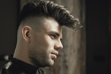 Portrait of a young unshaven man in a barbershop during a haircut