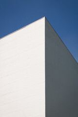 white wall, contrast between light and shadow, blue sky behind