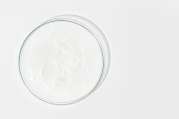 Petri dish on a light background. With a smear of white cream. Cosmetic cream, face mask, cream texture. View from above