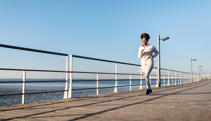 Motivated Black Female Jogger Running Outdoors On Wooden Pier Near Sea