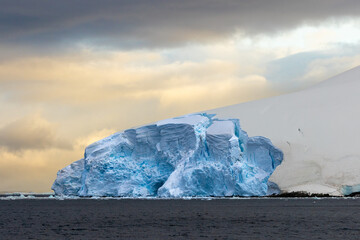 Impressive iceberg with blue ice and beautiful reflection on water in Antarctica, scenic landscape in Antarctic Peninsula	