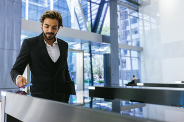 Businessman using card to open automatic gate machine in office building. Male using smart card to open automatic gate machine in office building. Working routine concept.
