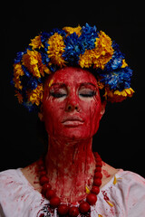 portrait of a girl in Ukrainian national clothes and jewelry with a wreath of blue and yellow flowers, blood on her face as a symbol of the war in Ukraine on a black background, vertical