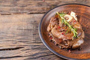 fried veal steak with seasonings in a frying pan, on a dark wooden background