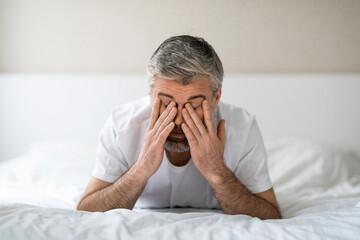 Exhausted middle aged man lying in bed in the morning