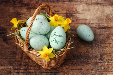 Panier avec jonquilles et oeufs de Pâques verts avec le texte Joyeuses Pâques.