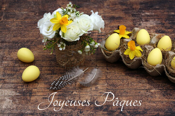 Carte de voeux Joyeuses Pâques : bouquet de fleurs avec des oeufs de Pâques sur un fond de bois.
