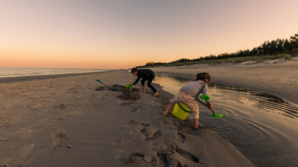 Kids having amazing time playing together at Baltic Sea after sunset, Poland