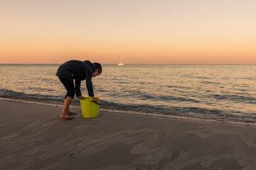 Boy having amazing time playing at Baltic Sea after sunset, Poland