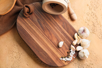 Wooden cutting board and spices on color background, closeup