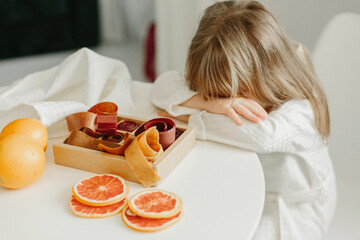 A girl in a white coat fell asleep sitting at a table on which marmalade stands - Powered by Adobe