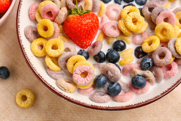 Bowl of colorful cereal rings with milk and berries on napkin