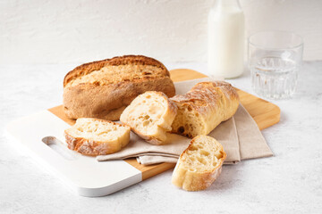 Board with slices of fresh bread on white table
