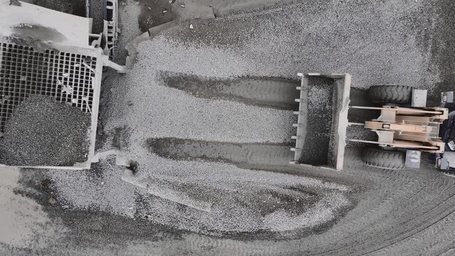 Excavator loads granite into sorter of crusher system at rock digging quarry upper view. Mineral deposits mining technology