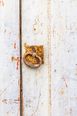 Rusted metal pull on an old wooden door.