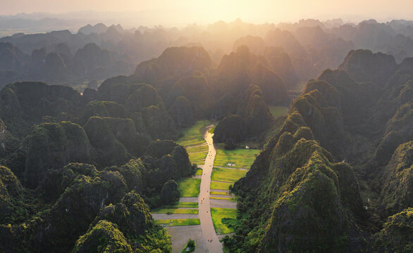 Aerial top view of fresh paddy rice and lake river, green agricultural fields with mountain hills valley in countryside or rural area of Ninh Binh, in Asia, Vietnam. Nature landscape background.