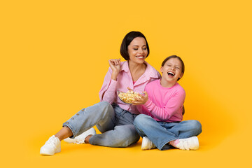 Obraz na płótnie Canvas Cheerful Mother And Little Daughter Easting Popcorn And Having Fun Together
