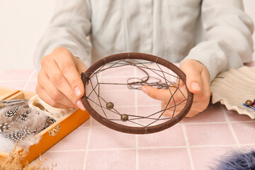 Woman making dream catcher on pink tile table, closeup