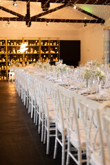 Served wedding table with decorative fresh white flowers and candles. Celebration details. Hanging flower beds and light bulbs Wedding decoration and decor, floristic concept