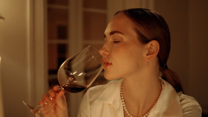 Exquisite woman drinking wine at candles place portrait. Lady tasting alcohol
