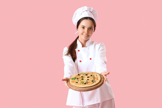 Female chef with tasty pizza on pink background