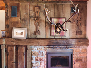 Typical decoration with fireplace and deer antlers in an accommodation, Vegacerneka village, Montaña de Riaño y Mampodre Regional Park, Leon province, Spain