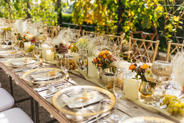 Wedding decorations. Served wedding table with golden plates, napkins, decorative fresh and dried flowers, candles and and light bulbs. Celebration details, wedding outdoor	
