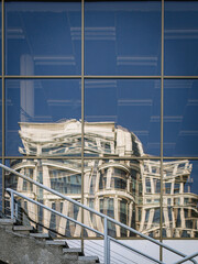 The white building in classical style is reflected in the glass stele. Broken reflection.