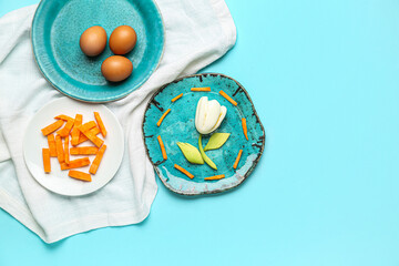 Plate with children's breakfast in shape of tulip, eggs and vegetables on blue background